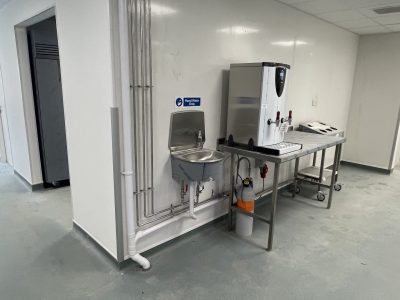 a white room with a water dispenser on a table next to a sink