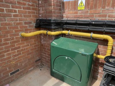 a green gas box sitting next to a yellow pipe