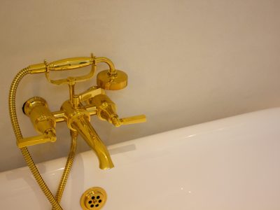 a close up shot of a golden tap in a bathroom on a plumbing project