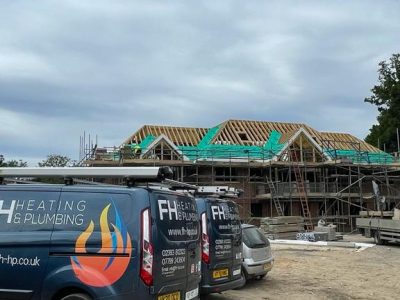 two vans and a car parked outside a house under construction