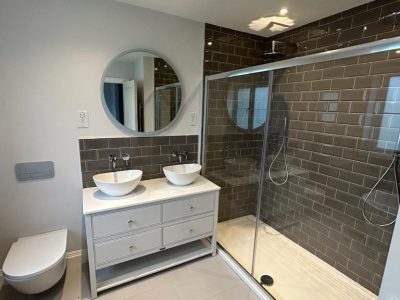 a bathroom with two sinks, a toilet and large shower